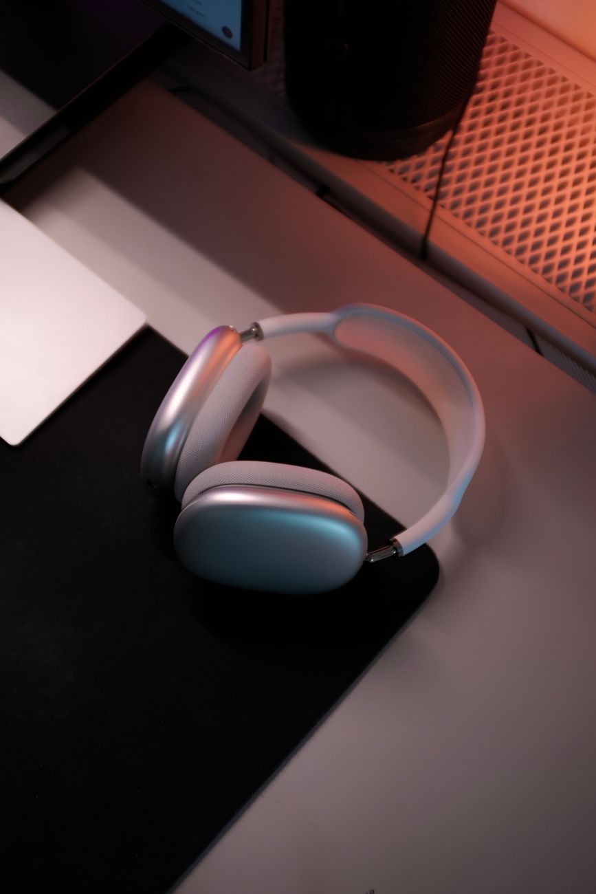 A stylish pair of wireless headphones resting on a desk with ambient lighting.