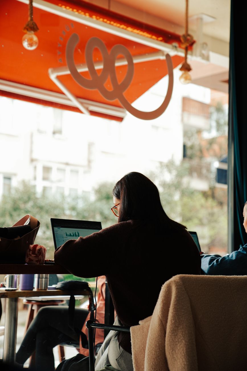 Group of adults working on laptops in a cozy indoor cafe setting.